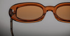 Close-up of Jacques Marie Mage Besset sunglasses, brown oval lenses with transparent frames, photographed from the front.