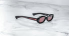 Jacques Marie Mage Besset black oval sunglasses with pink-tinted UV lenses, shown from above.