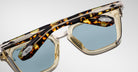 Close-up of Jacques Marie Mage Borodino eyeglasses featuring blue lenses, yellow frames, and a tortoiseshell brow bar.