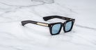 Jacques Marie Mage Quentin sunglasses with blue-tinted lenses and gold accents, viewed from above.
