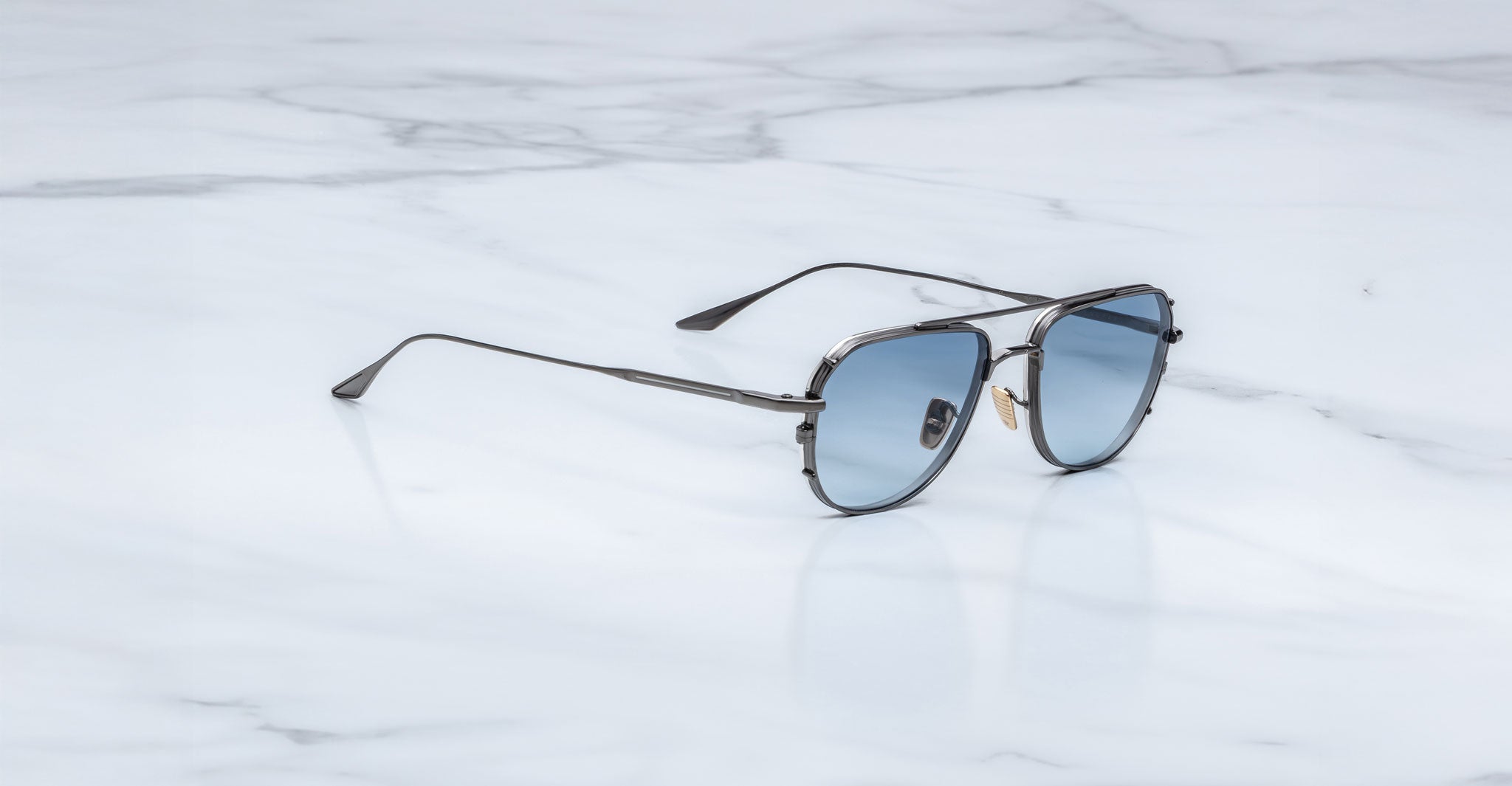 Jacques Marie Mage Cendrars aviator sunglasses with blue lenses, front view, displayed on a flat surface.