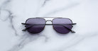 Jacques Marie Mage Cendrars black aviator sunglasses with dark lenses, top view.