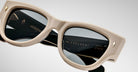 A close up view of a pair of Jacques Marie Mage Chelsea beige, thick-framed sunglasses with dark lenses