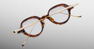 Jacques Marie Mage The Clark eyeglasses with gold temples shown upside down; top-down view highlights frame and temple details.