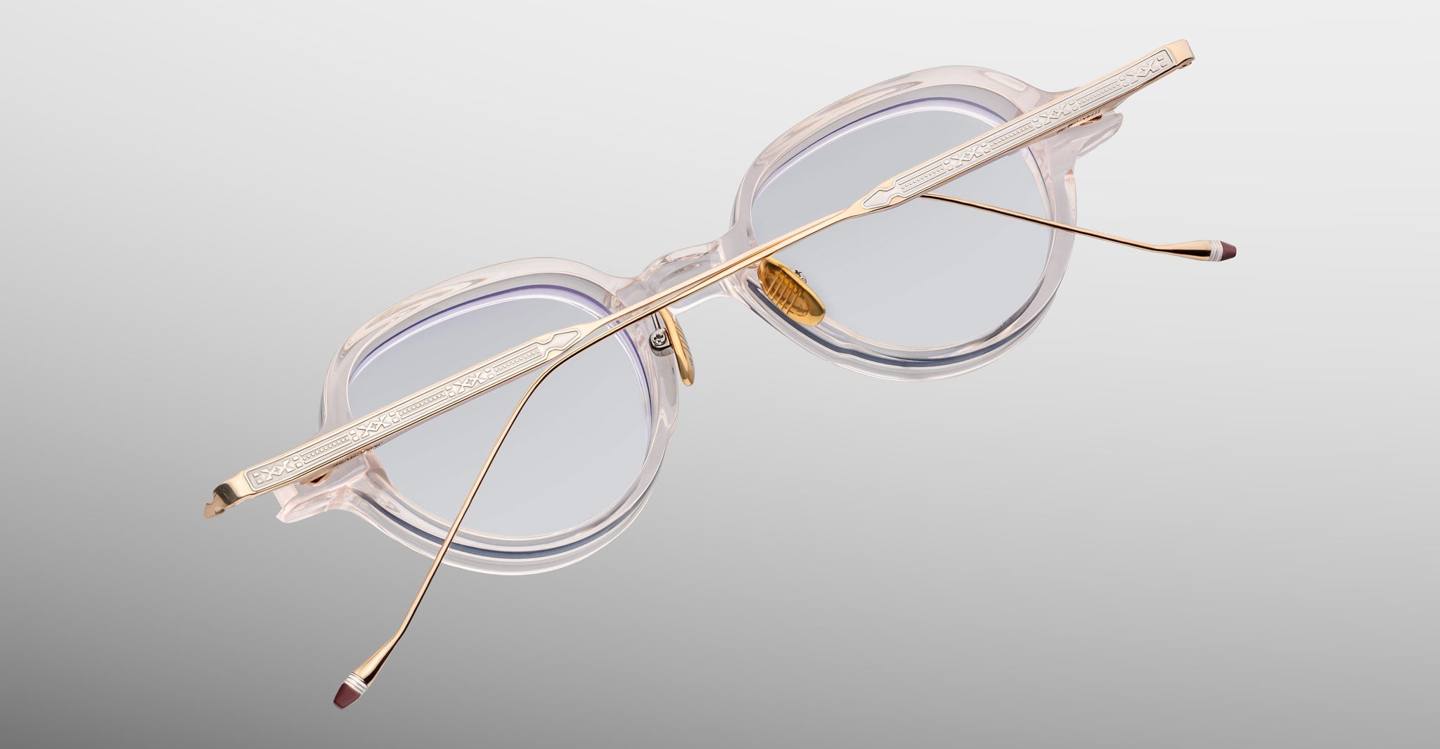 The Jacques Marie Mage Clark eyeglasses feature round, midcentury-inspired optical frames and gold metal temples, shown from a rear angled view against a light gray background, capturing the refined style of Jacques Marie Mage.
