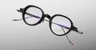 Jacques Marie Mage The Clark eyeglasses feature clear lenses and slim metal arms, shown from the front.