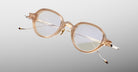 Jacques Marie Mage The Clark eyeglasses, clear beige round frames with silver arms, shown from the front.