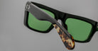 Close-up of Jacques Marie Mage Cleavon sunglasses, featuring green lenses, black frame, and tortoiseshell temple tips.