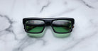 Jacques Marie Mage Cleavon black rectangular sunglasses with green lenses, shown from above.