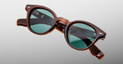Jacques Marie Mage Clemens in Hickory brown-framed sunglasses with green lenses, front view.