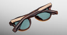Jacques Marie Mage Clemens in Hickory tortoiseshell sunglasses with green lenses, shown folded and viewed from the back.