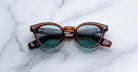Jacques Marie Mage Clemens in Hickory round brown sunglasses with blue-tinted lenses, front view, product type: sunglasses.