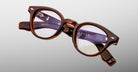 Jacques Marie Mage Clemens in Hickory brown acetate eyeglasses with clear lenses, silver accents, and subtle branding, front view.