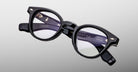 Jacques Marie Mage Clemens in Obscure black round blue light eyeglasses with thick frames and silver accents, front view.