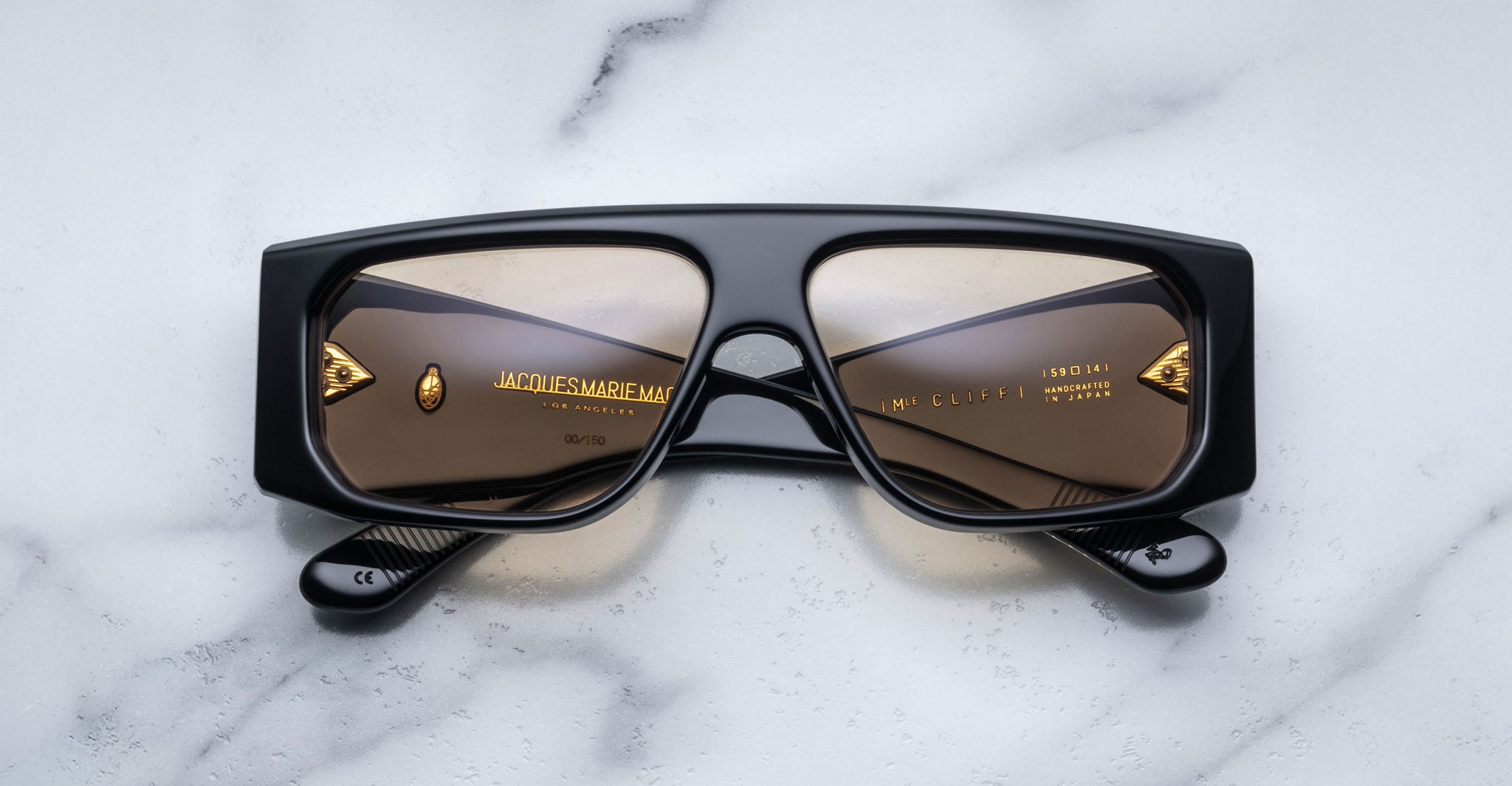 Jacques Marie Mage Cliff sunglasses, black frame with brown lenses, folded, top view.
