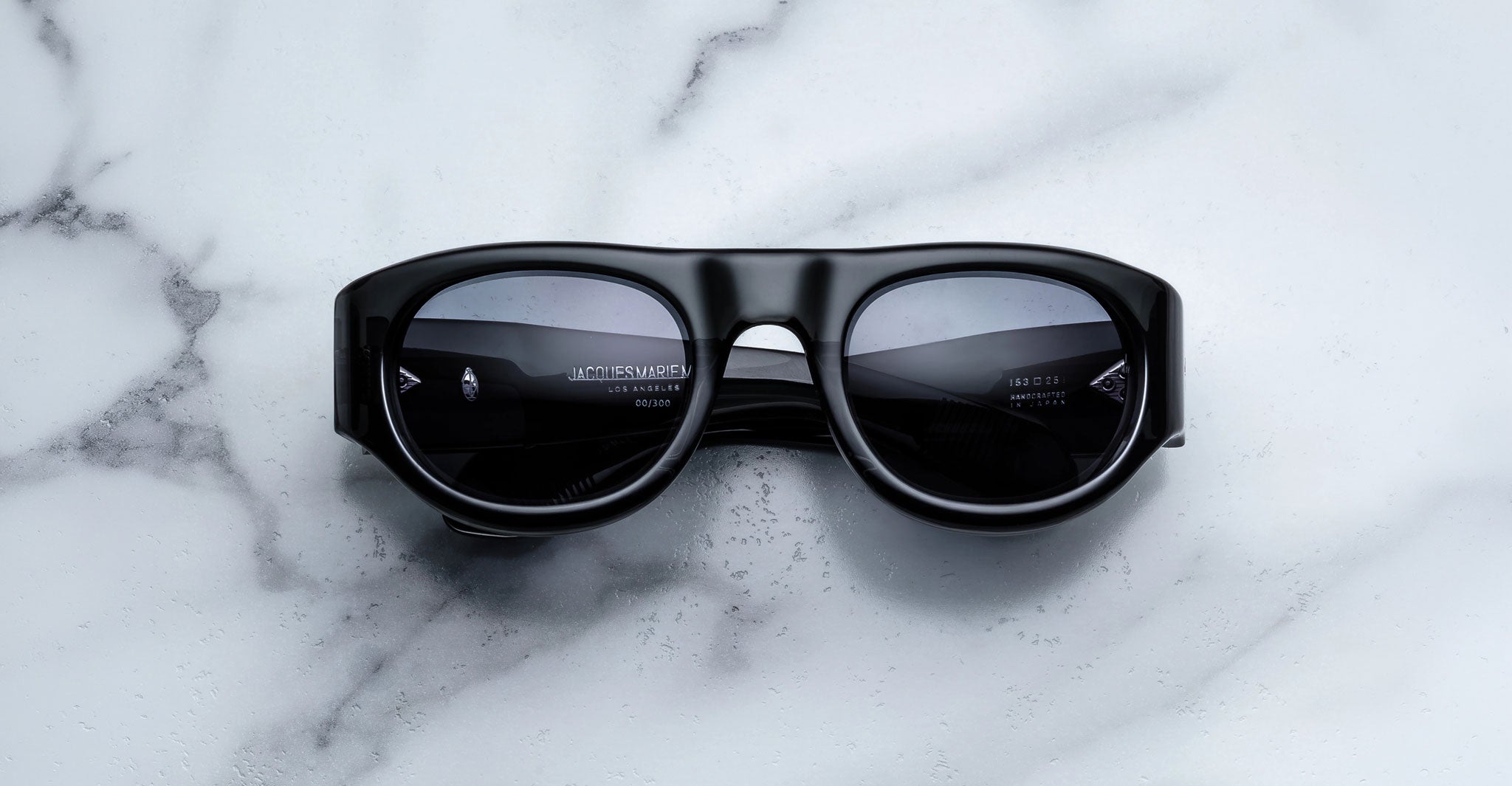 Front view of the Jacques Marie Mage Clyde 2.0 sunglass in Grisaille Black acetate with dark grey lenses on a marble background