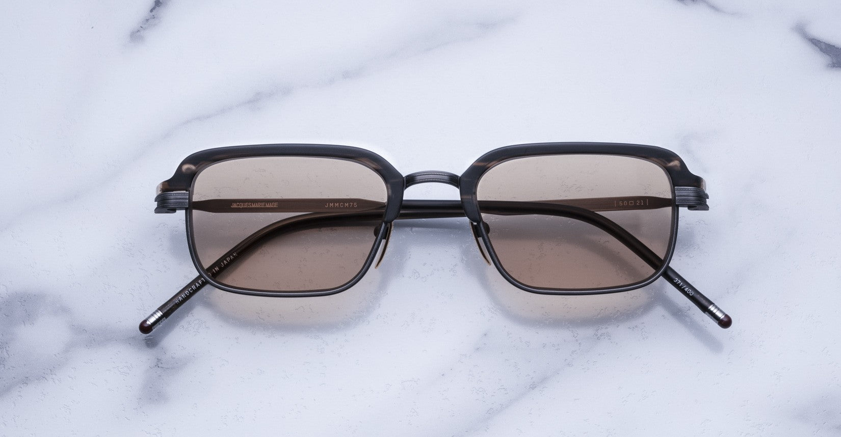 Jacques Marie Mage Comanche: handcrafted rectangular sunglasses with dark frames and brown-tinted lenses, shown on white marble—ideal for those seeking exclusive, limited-edition eyewear.