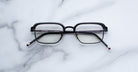 Jacques Marie Mage Comanche in Corbeau black rectangular eyeglasses shown from above, featuring full-rim frame on a flat surface.