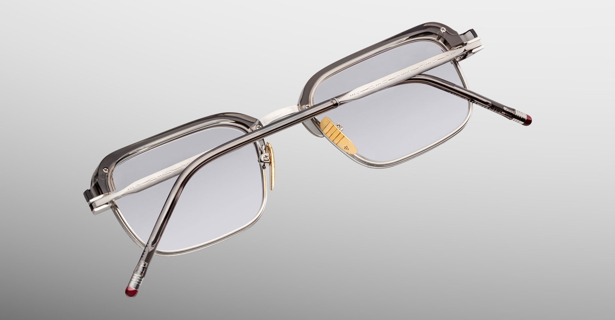 The Jacques Marie Mage Comanche limited-edition eyeglass frames feature a rectangular shape with clear frames, metal arms, and clear lenses, displayed from an angled rear view on a plain background.