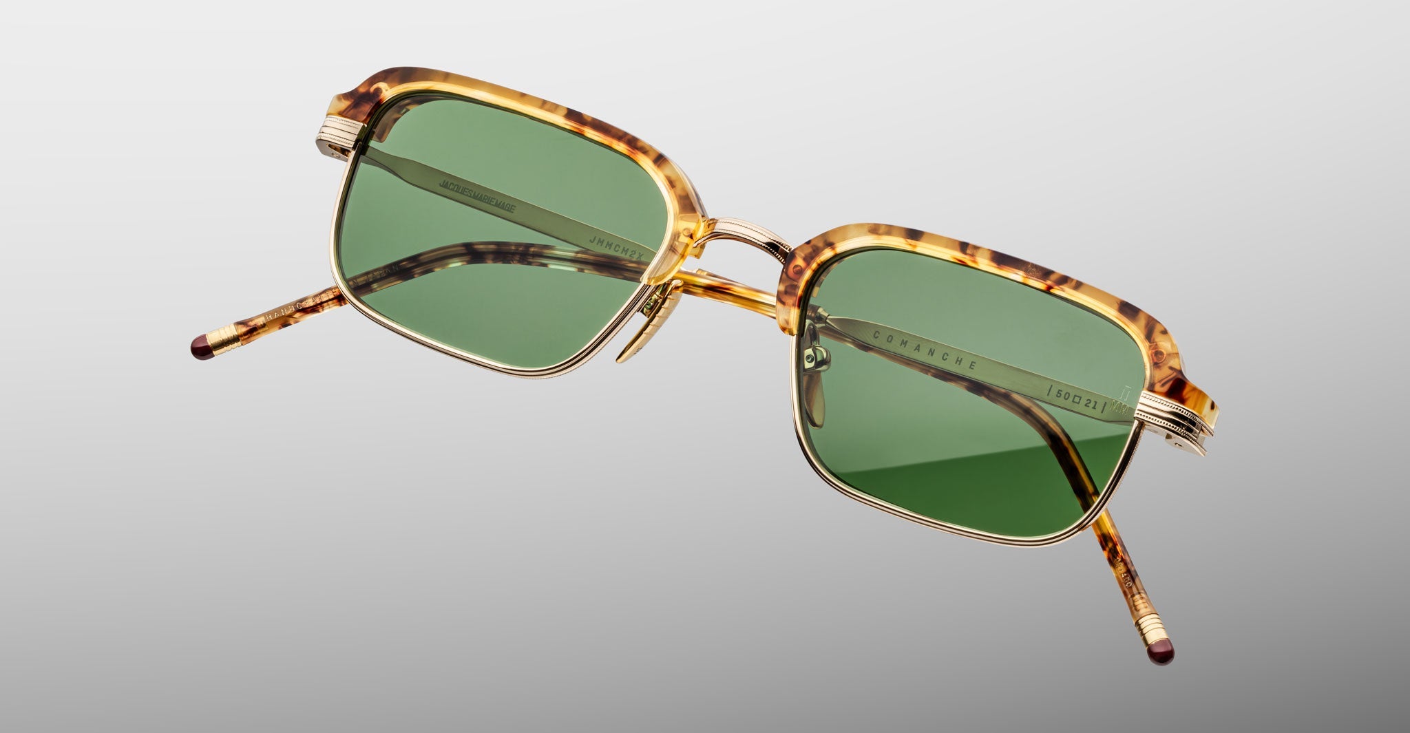 The Jacques Marie Mage Comanche sunglasses feature a handcrafted rectangular tortoiseshell frame and green lenses, shown against a light gray background.
