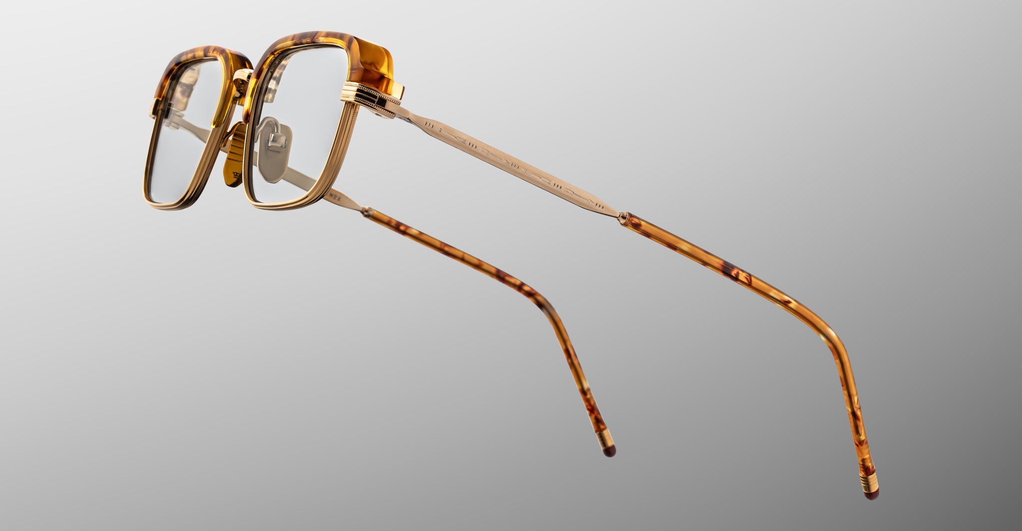 The Jacques Marie Mage Comanche features tortoiseshell rectangular frames and sleek metal arms, displayed on a plain gray background—ideal for anyone seeking exclusive, limited-edition eyewear.