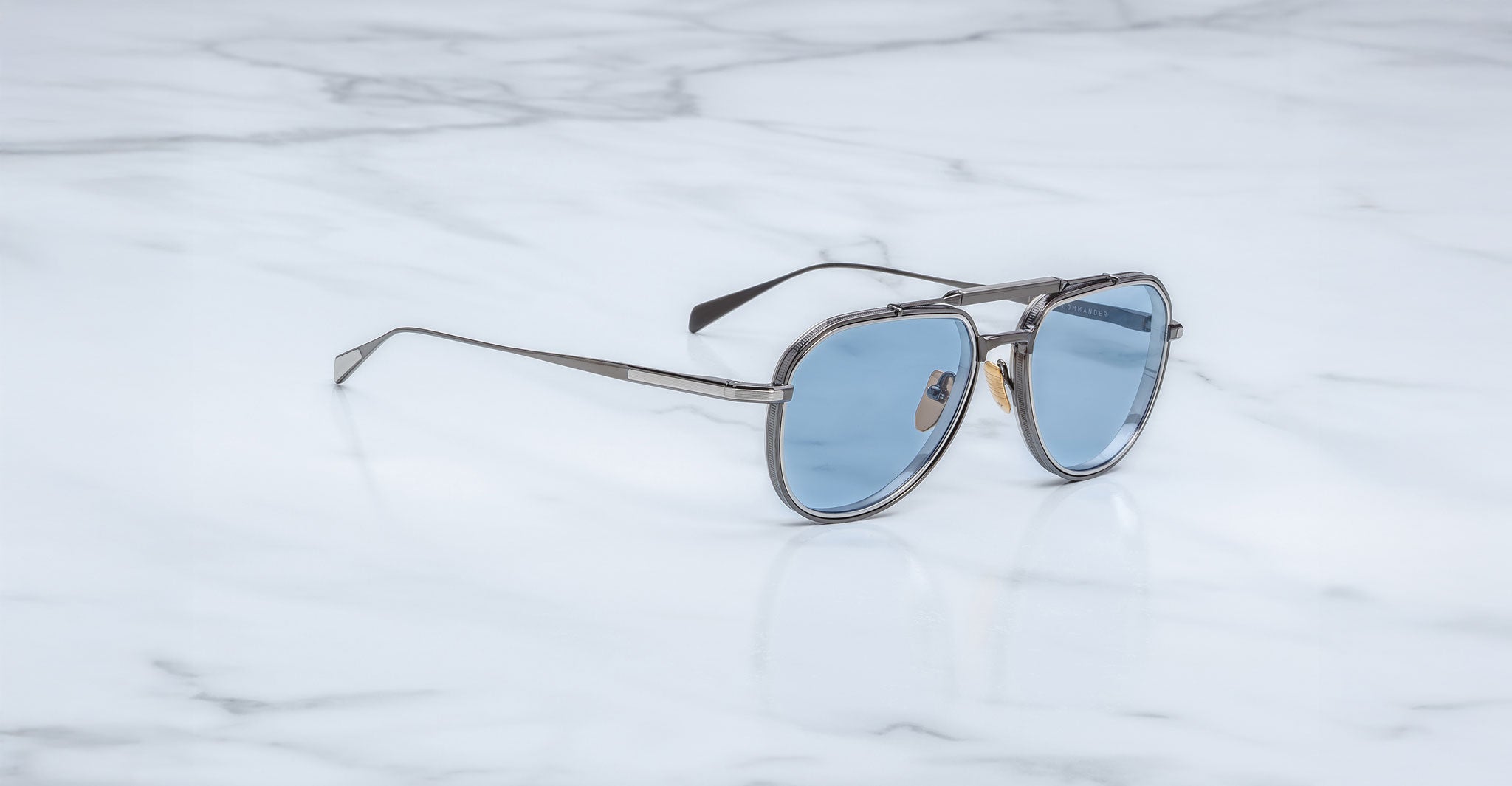Angled view of Jacques Marie Mage Commander in Antique Silver, featuring an antique silver-tone titanium aviator frame with double bridge, engraved rims, and cool blue lenses with a clean, modern finish.