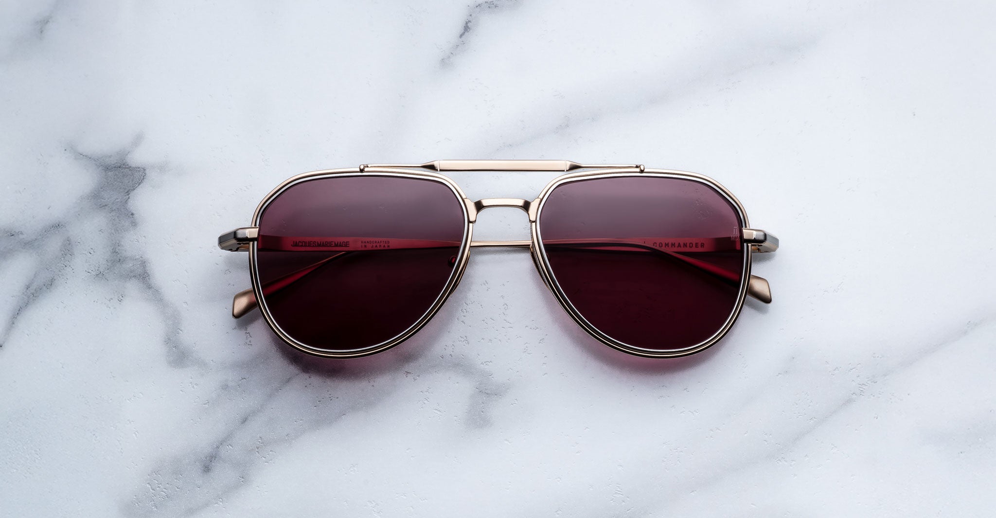 Front-facing view of Jacques Marie Mage Commander in Champagne, featuring a light gold-tone double-bridge titanium frame with aviator lenses in a rich rose-champagne tint and finely engraved rims.