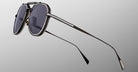 Close-up of Jacques Marie Mage Commander sunglasses with dark lenses, thin black metal frames, and a double bridge design, displayed against a plain gradient gray background.