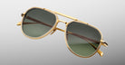 Three-quarter view of Jacques Marie Mage Commander in Musket, showcasing the gold-tone double-bridge frame, engraved aviator rims, and green lenses with a refined, military-inspired silhouette.