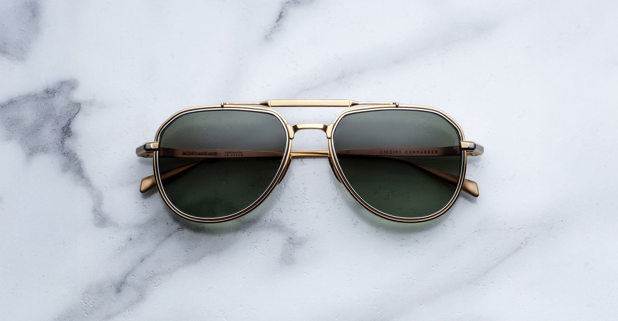 Front-facing view of Jacques Marie Mage Commander in Musket, featuring a gold-tone double-bridge titanium frame with teardrop aviator lenses in deep green and finely detailed rims.