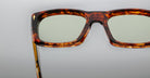 Close-up of the upper half of Jacques Marie Mage Corniche tortoiseshell square eyeglass frames with slightly tinted lenses, set against a plain gray background.
