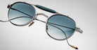 Detailed front view of the Jacques Marie Mage Dasan titanium sunglass in silver with blue gradient lenses on a white background