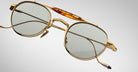 Detailed front view of the Jacques Marie Mage Dasan titanium sunglass in gold color with light grey lenses on a white background