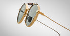 Detailed profile view of the Jacques Marie Mage Dasan titanium sunglass in gold color with light grey lenses on a white background