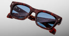 The Jacques Marie Mage Dealan 53 sunglasses feature brown tortoiseshell rectangular frames with blue-tinted lenses, shown against a light gray background.