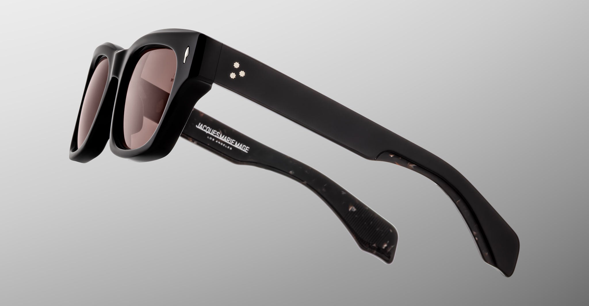Jacques Marie Mage Dealan 53: Black rectangular sunglasses with thick frames and brown-tinted lenses, shown from a side angle on a light gray background.