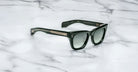 Jacques Marie Mage Dealan black sunglasses with dark lenses and metallic arms, shown from above.