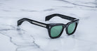 Jacques Marie Mage Dealan sunglasses with green lenses and metal accents, viewed from above.