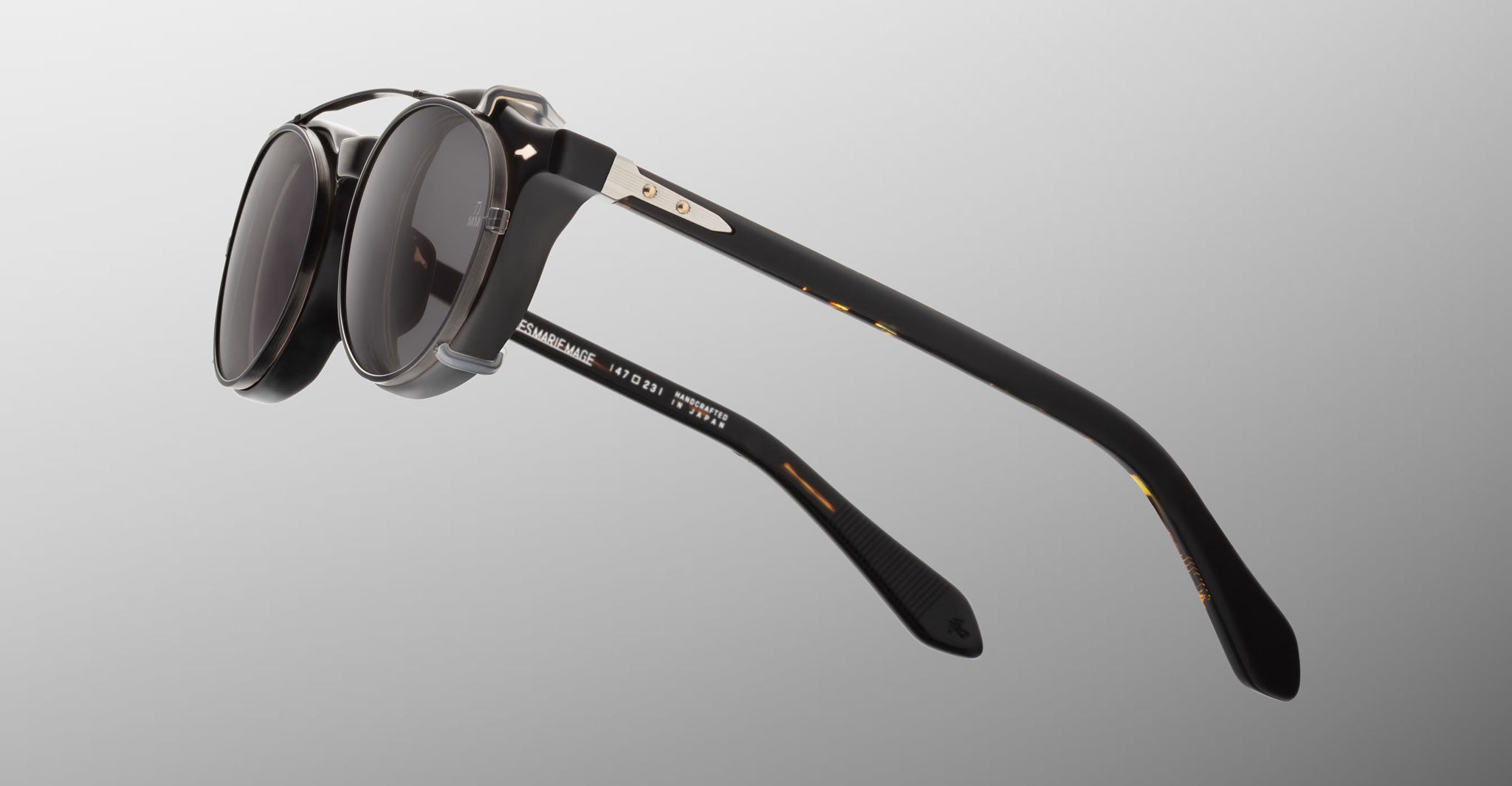 Jacques Marie Mage Demoncey Clip-On sunglasses, front view, feature bold black round thick frames and metal accents.
