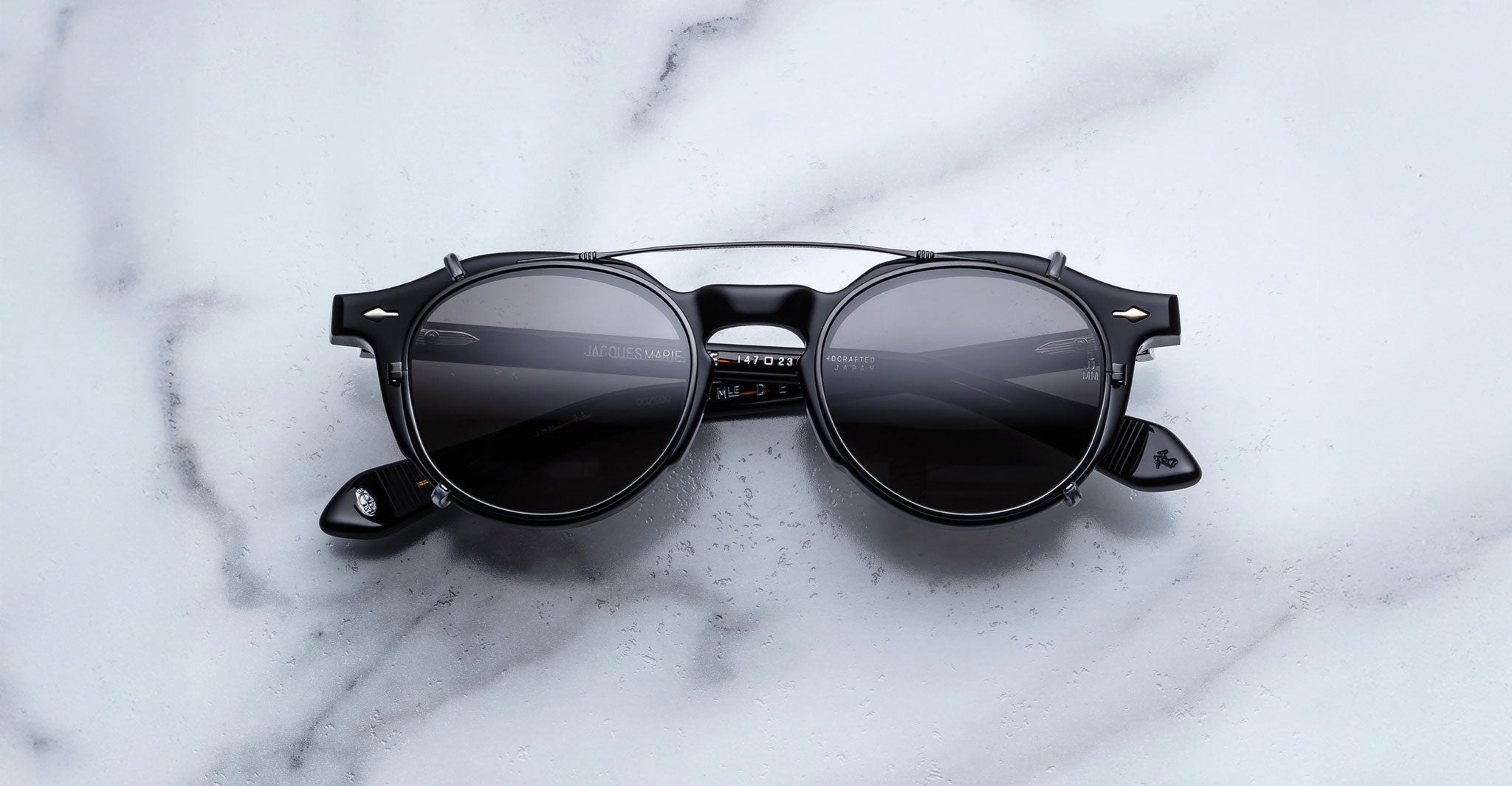Jacques Marie Mage Demoncey Clip-On sunglasses with dark lenses, top view.
