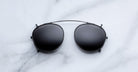 Jacques Marie Mage Demoncey Clip-On sunglasses with black aviator frames and dark lenses, shown from the front.