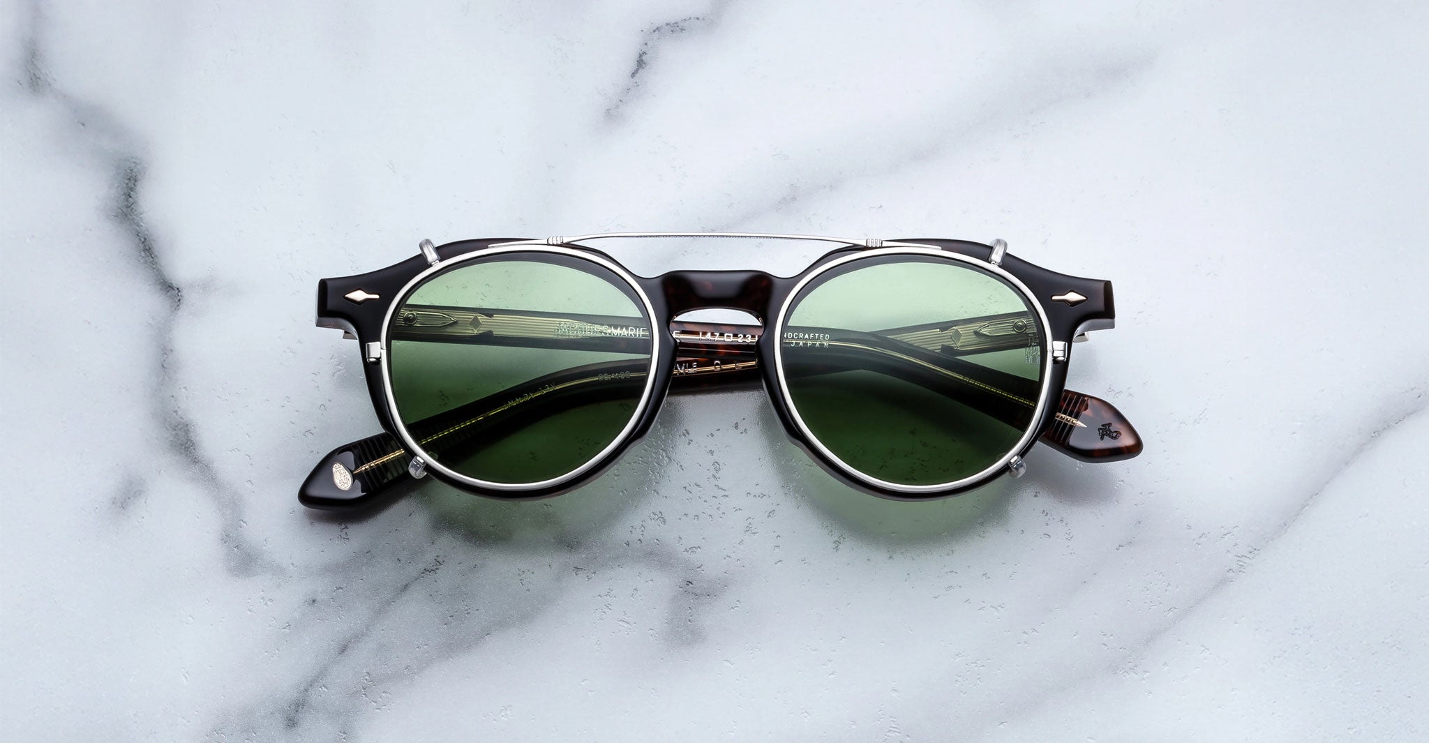 Jacques Marie Mage Demoncey Clip-On sunglasses, green lenses, dark frames, shown from above.