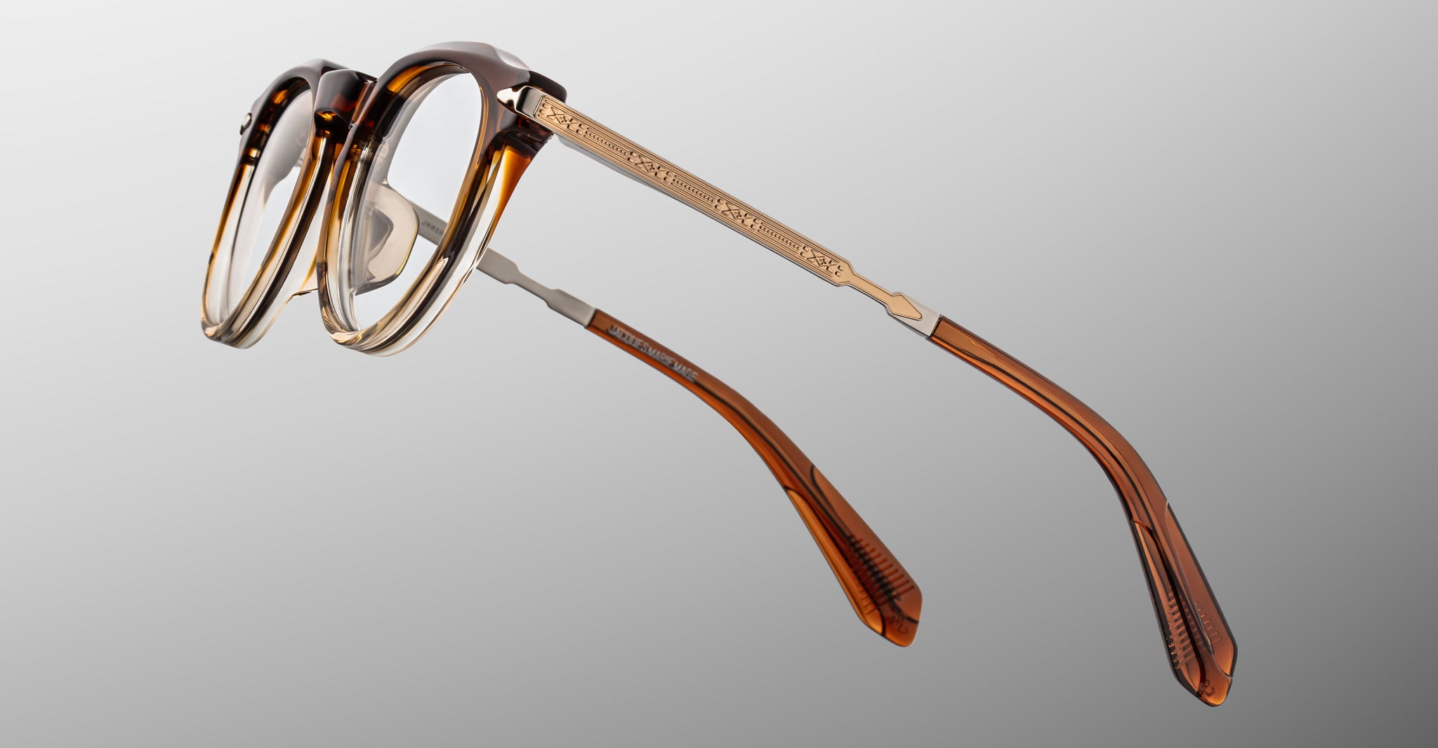 Jacques Marie Mage Desnos eyeglasses, shown from the front, have brown and gold frames with engraved metal temples.