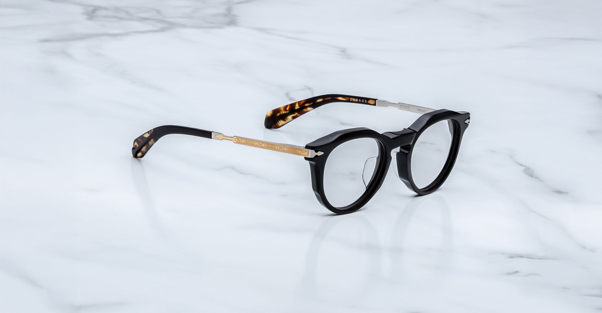 Jacques Marie Mage Desnos black round eyeglasses with gold arms and tortoiseshell tips, top view.