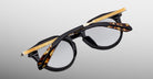 Jacques Marie Mage Desnos sunglasses, round shape, black and tortoiseshell frame, silver lenses, gold temples, front view.