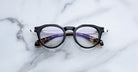 Jacques Marie Mage Desnos eyeglasses with round black frames and tortoiseshell arms, shown from above.