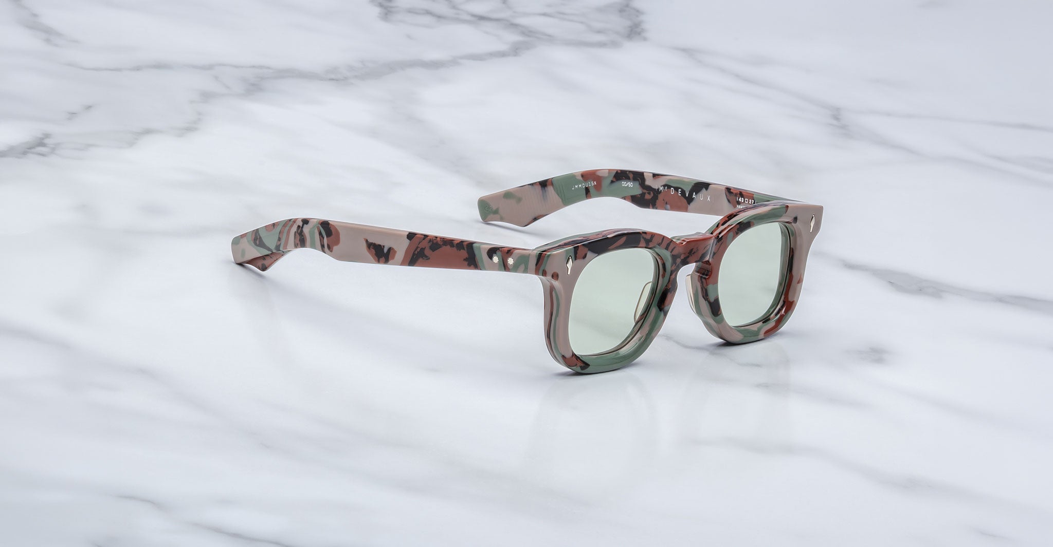 3/4 view of Jacques Marie Mage Devaux optical frame in Sergeant camoflauge pattern with clear lenses on a marbled background