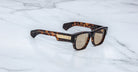 Jacques Marie Mage Dino in Agar tortoiseshell acetate sunglass frame with brown lenses, gold arrowhead pins, and sculptural wide temples