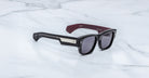 Jacques Marie Mage Dino in Bloodstone black acetate sunglass frame with grey lenses, gold arrowhead pins, and sculptural wide temples, three-quarter view showing front and temple profile
