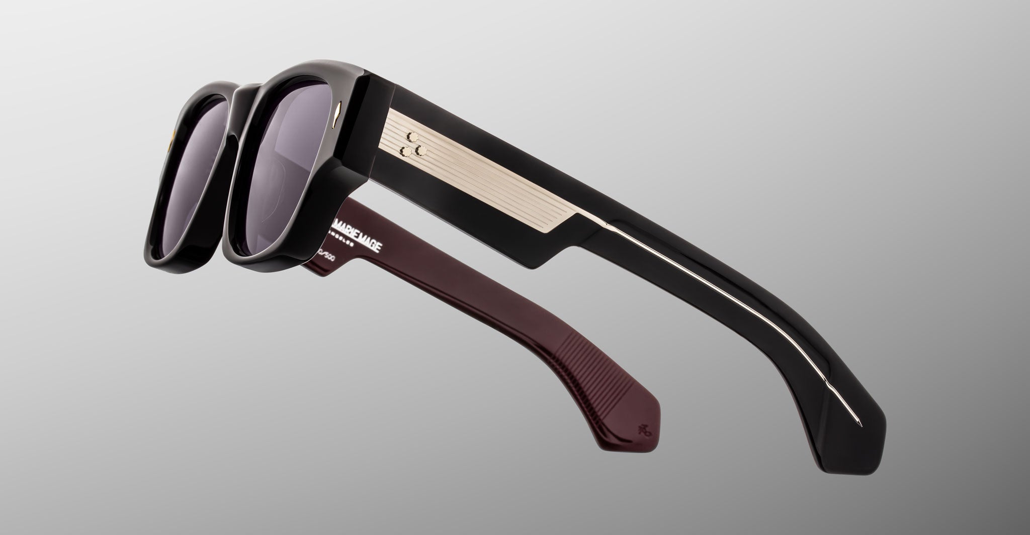 Jacques Marie Mage Dino in Bloodstone black acetate sunglass frame with grey lenses, gold arrowhead pins, and sculptural wide temples, side view showing engraved wirecore and temple detail